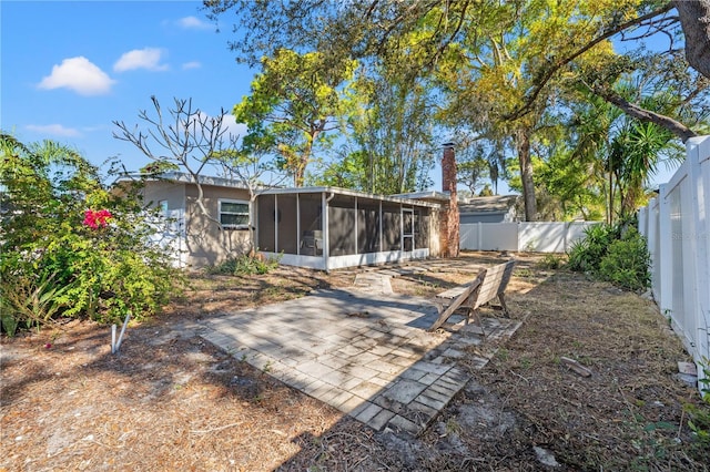 rear view of property with a patio, a fenced backyard, a sunroom, and a chimney