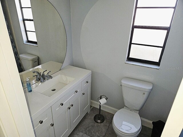 bathroom with tile patterned flooring, toilet, vanity, and baseboards