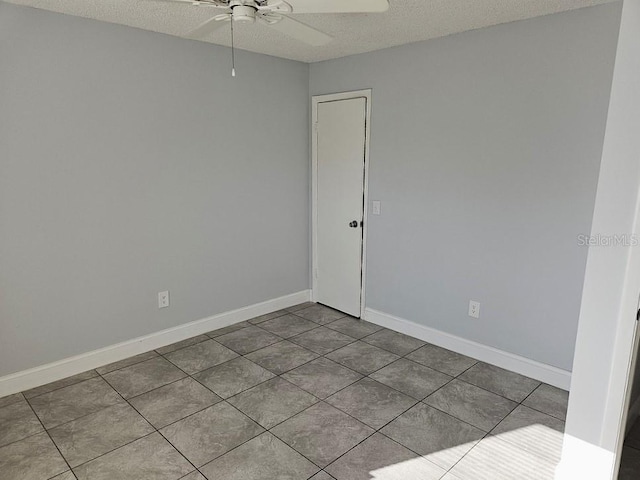 empty room with ceiling fan, baseboards, tile patterned flooring, and a textured ceiling