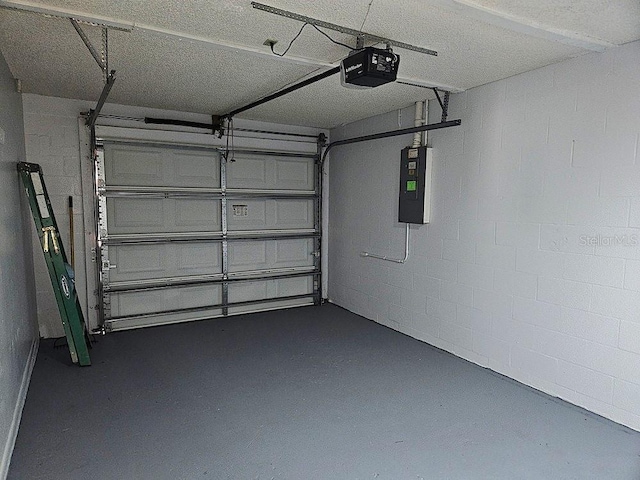 garage with electric panel, a garage door opener, and concrete block wall