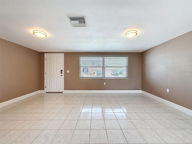 empty room featuring light tile patterned flooring, baseboards, and visible vents