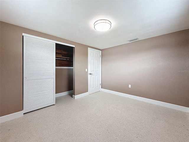 unfurnished bedroom with a closet, visible vents, speckled floor, and baseboards