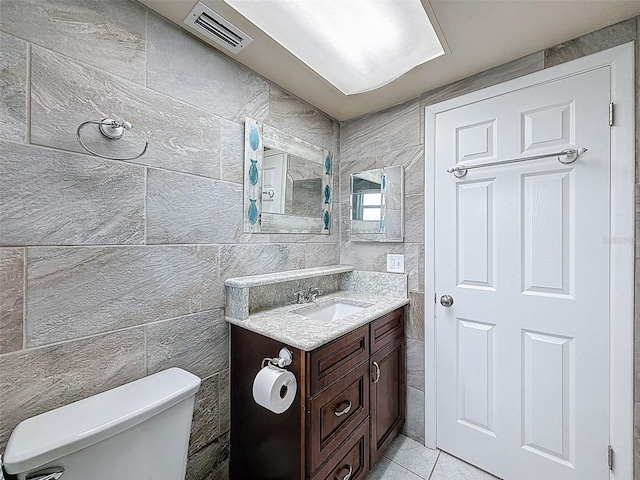 bathroom featuring tile patterned floors, visible vents, toilet, tile walls, and vanity