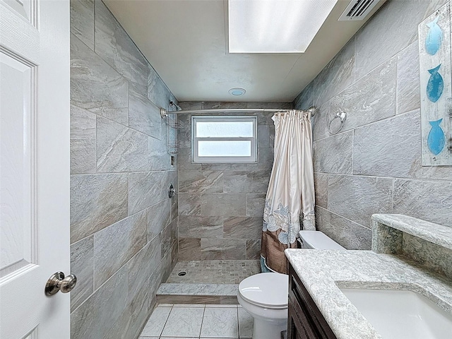 full bath featuring vanity, visible vents, a tile shower, tile walls, and toilet