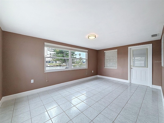 unfurnished room featuring light tile patterned flooring, visible vents, and baseboards