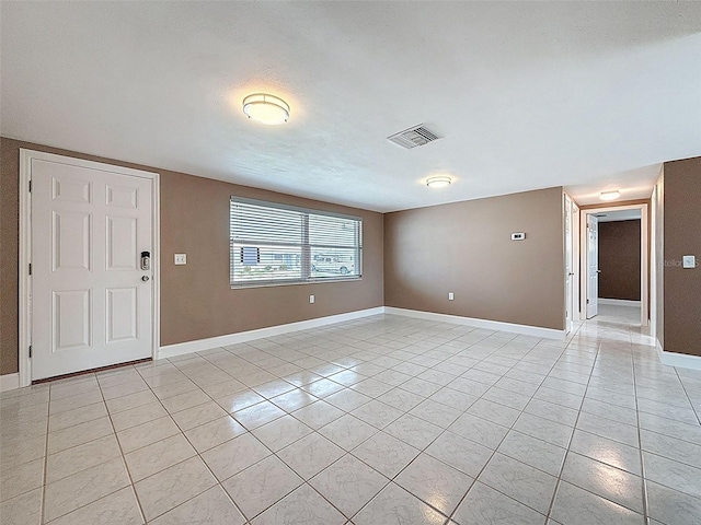 spare room with light tile patterned floors, visible vents, and baseboards