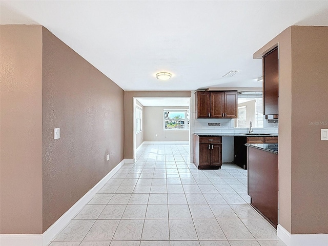 kitchen featuring light tile patterned floors, dark brown cabinets, visible vents, and a wealth of natural light