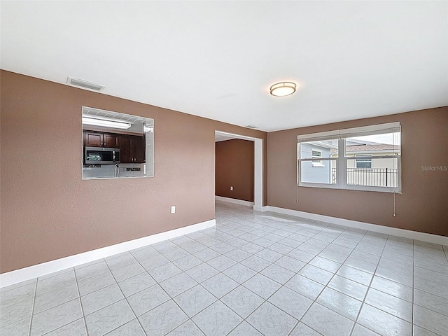 spare room featuring light tile patterned flooring, visible vents, and baseboards