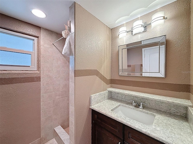 bathroom with vanity, walk in shower, and a textured wall