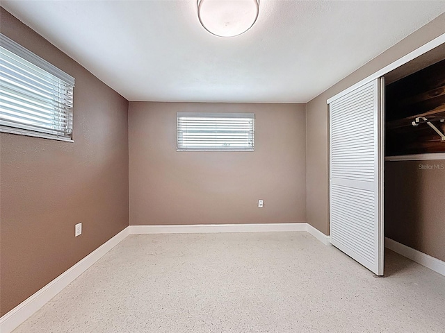 unfurnished bedroom featuring a closet, multiple windows, and baseboards