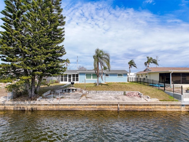 back of property featuring fence, a sunroom, and a water view