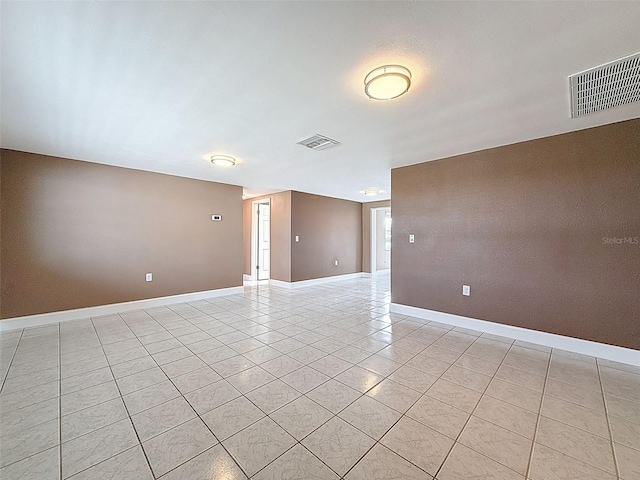 empty room with light tile patterned floors, baseboards, and visible vents