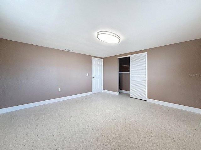 unfurnished bedroom featuring a closet, visible vents, light speckled floor, and baseboards