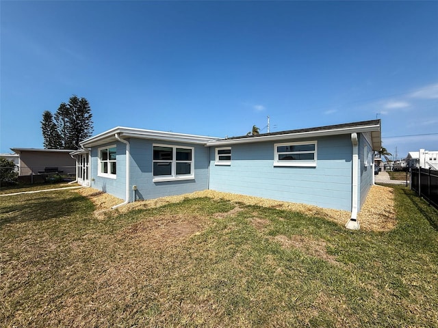 back of property with concrete block siding, a yard, and fence