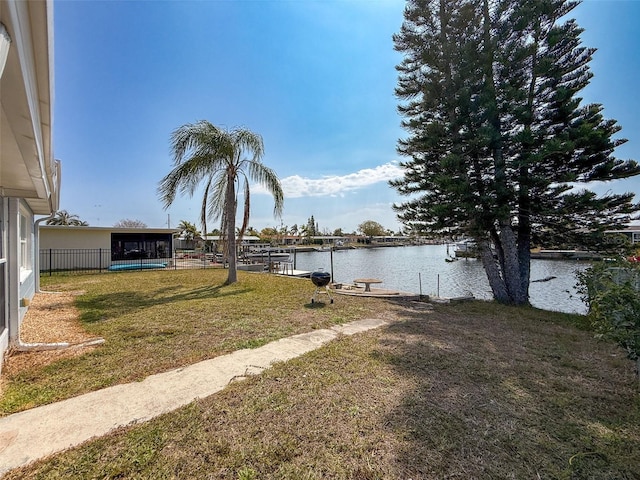 view of yard featuring fence, a water view, and a boat dock