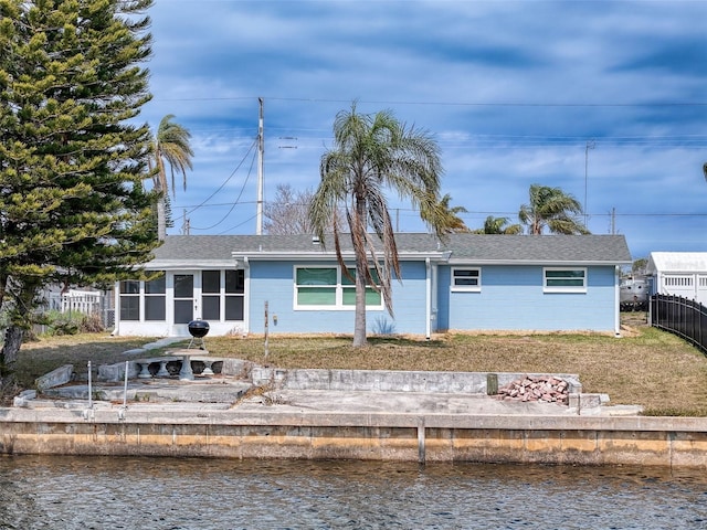 rear view of house featuring fence, roof with shingles, and a water view