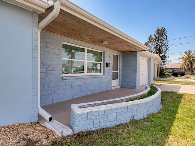 entrance to property featuring stone siding, driveway, and an attached garage