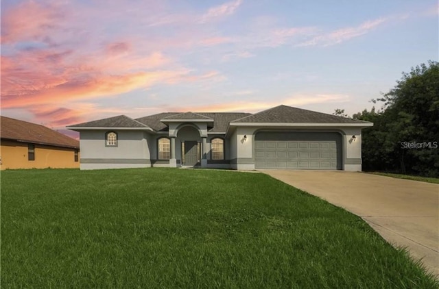 view of front of house with stucco siding, an attached garage, driveway, and a yard