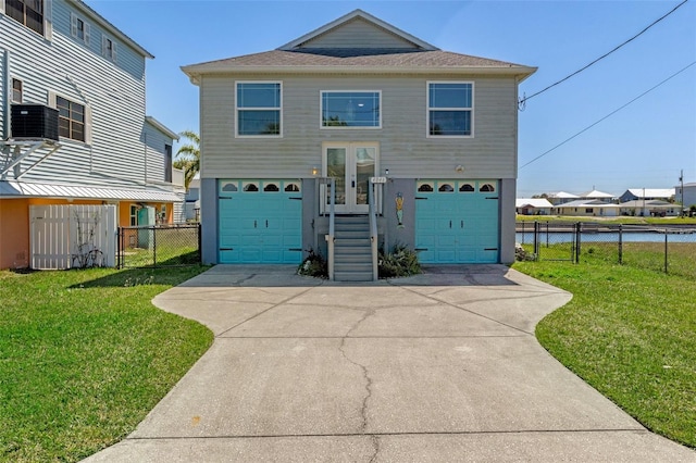 coastal home featuring french doors, concrete driveway, a front yard, and fence