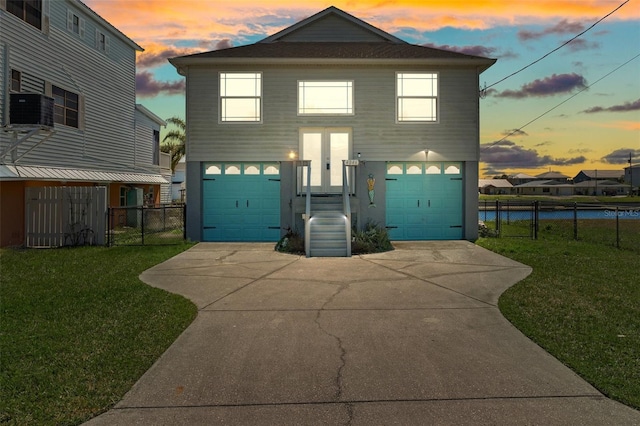 view of front of home with a yard, a garage, driveway, and fence