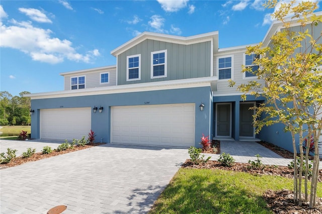 view of front of property featuring board and batten siding, an attached garage, decorative driveway, and stucco siding