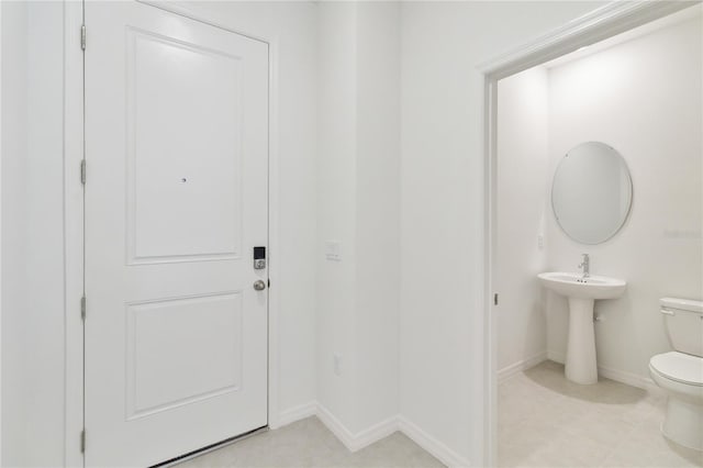 bathroom featuring baseboards, tile patterned flooring, and toilet