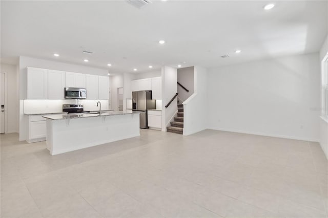 unfurnished living room featuring recessed lighting, a sink, stairs, and baseboards