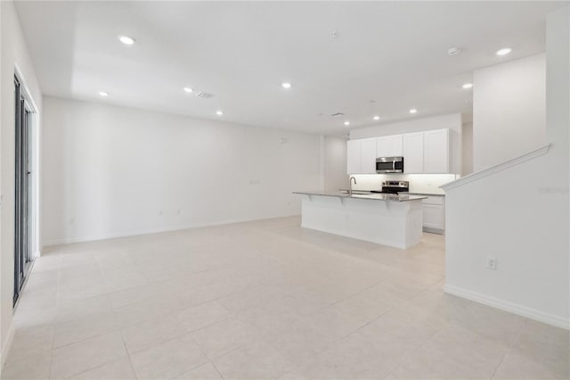unfurnished living room featuring recessed lighting, baseboards, light tile patterned floors, and a sink