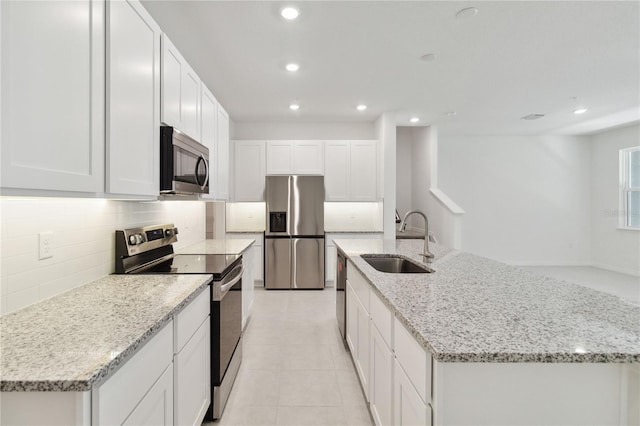 kitchen featuring appliances with stainless steel finishes, a sink, an island with sink, recessed lighting, and tasteful backsplash