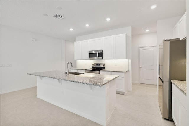 kitchen featuring a kitchen bar, appliances with stainless steel finishes, a sink, white cabinets, and an island with sink
