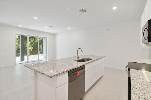 kitchen featuring light stone countertops, a center island with sink, stainless steel microwave, a sink, and dishwasher