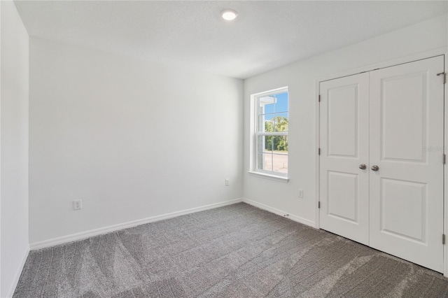 unfurnished bedroom with carpet flooring, baseboards, and a closet