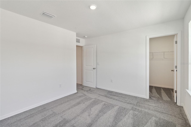 unfurnished bedroom with visible vents, baseboards, a closet, a spacious closet, and carpet