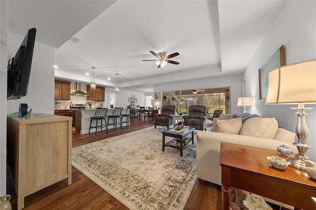16386 Heron Hills Dr, Spring Hill, FL 34610 - living area featuring a tray ceiling, visible vents, ceiling fan, and dark wood-style flooring