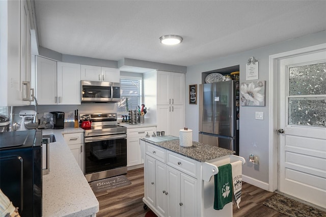 kitchen with light stone counters, stainless steel appliances, dark wood-style flooring, and white cabinetry