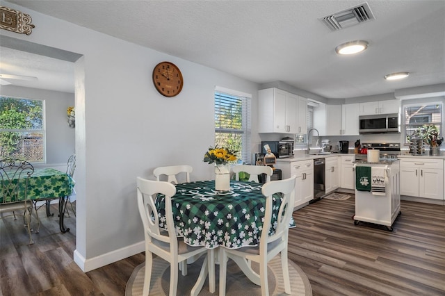 dining room with visible vents, dark wood-type flooring, baseboards, a textured ceiling, and a ceiling fan