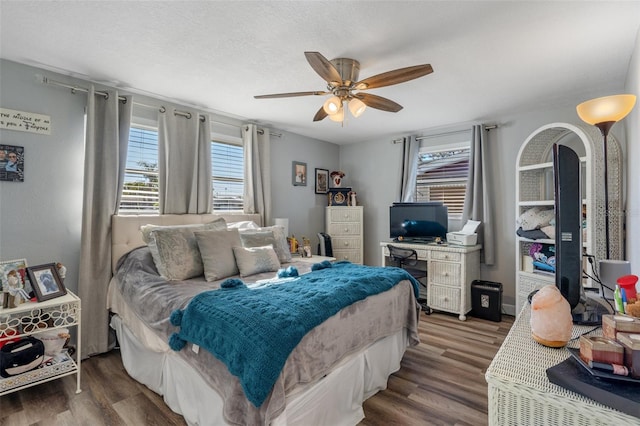 bedroom with a ceiling fan, wood finished floors, and a textured ceiling