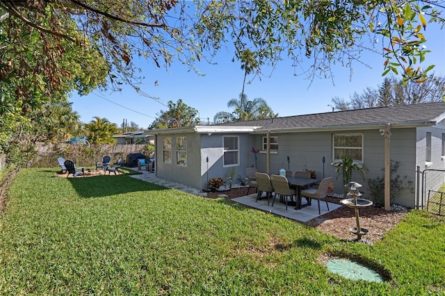 back of property with stucco siding, a lawn, a patio, fence, and a fire pit