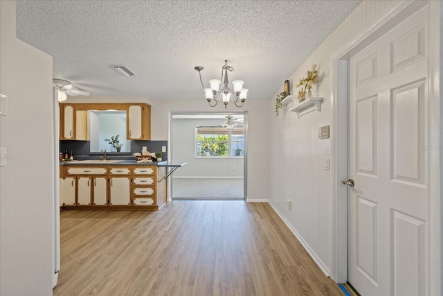 3728 Linkwood St, New Port Richey, FL 34652 - kitchen featuring dark countertops, a textured ceiling, light wood-style floors, an inviting chandelier, and visible vents
