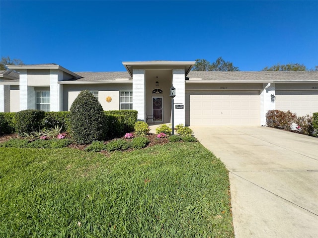 view of front of home with brick siding, a front lawn, concrete driveway, and a garage