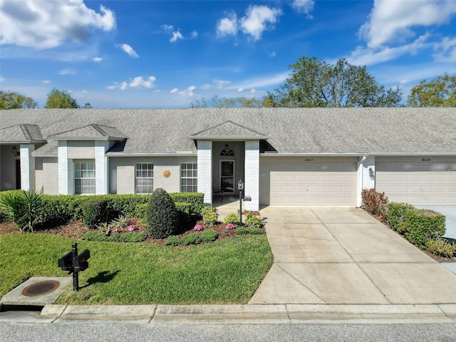 single story home with brick siding, a shingled roof, concrete driveway, a front yard, and a garage