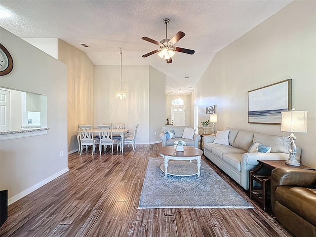 living area with baseboards, a textured ceiling, wood finished floors, and ceiling fan with notable chandelier