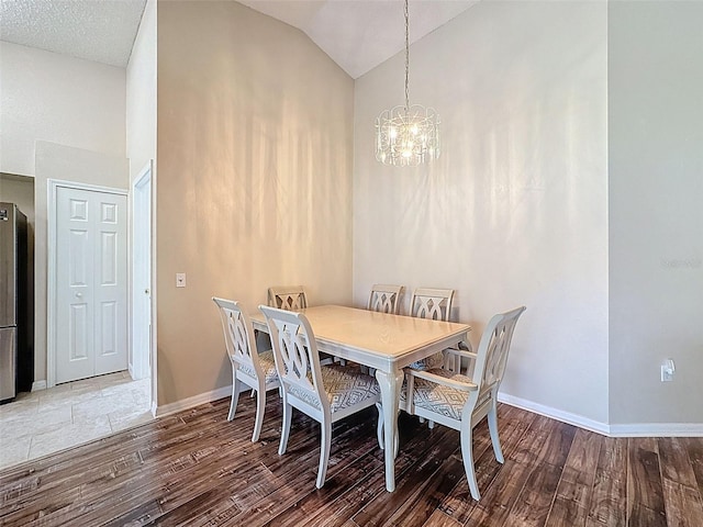 dining room featuring baseboards, a notable chandelier, wood finished floors, and high vaulted ceiling