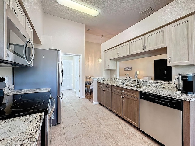 kitchen featuring a sink, light stone countertops, visible vents, and stainless steel appliances