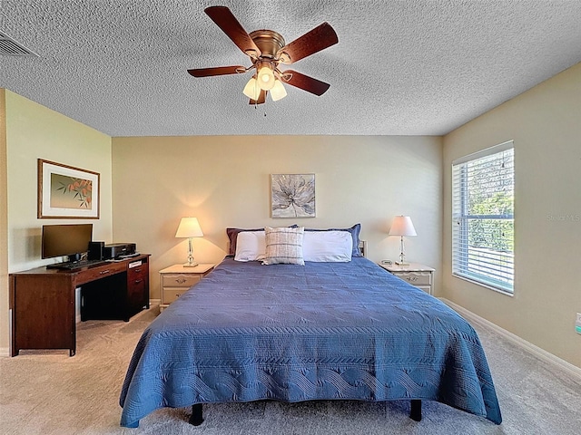 bedroom with visible vents, light colored carpet, a textured ceiling, and ceiling fan