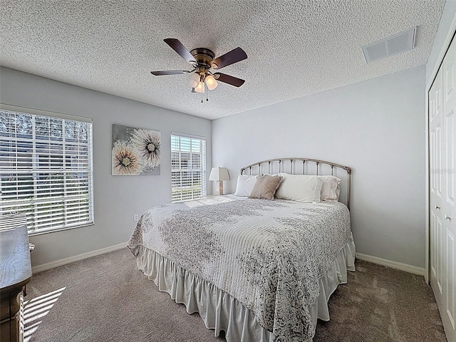 carpeted bedroom featuring visible vents, a ceiling fan, a textured ceiling, a closet, and baseboards