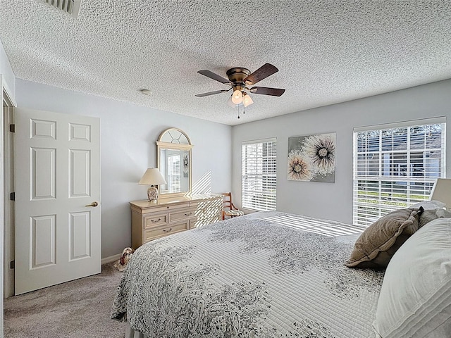 carpeted bedroom with visible vents, a textured ceiling, and ceiling fan