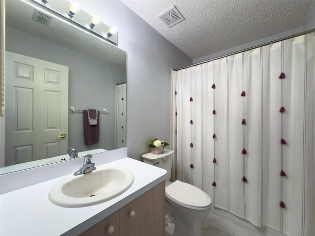 bathroom with vanity, toilet, visible vents, and a textured ceiling