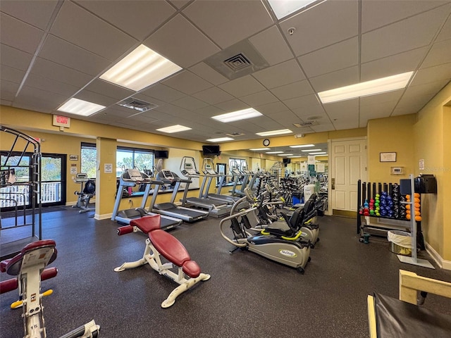 exercise room featuring a paneled ceiling, visible vents, and baseboards