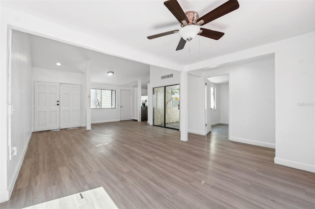 unfurnished living room featuring visible vents, baseboards, light wood-style floors, and a ceiling fan